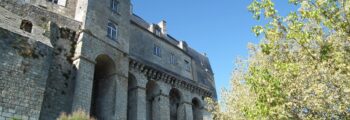 Mosquée blanche sur pilotis, dôme bleu, ciel clair.